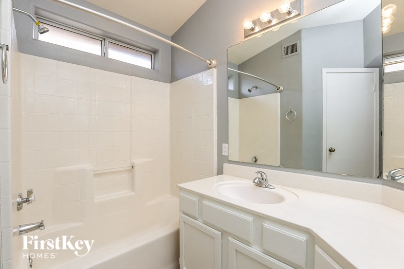 a bathroom with a white sink and a shower and a mirror