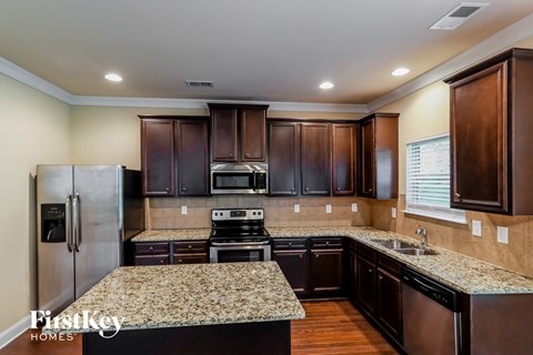 a kitchen with granite counter tops and wooden cabinets and stainless steel appliances