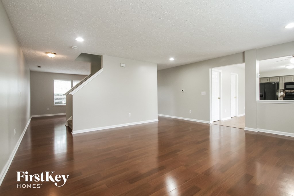 A spacious room with wooden floors and a staircase leading to another room.