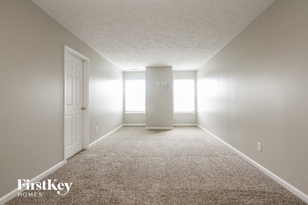 A carpeted hallway with a door on the left and a door on the right.