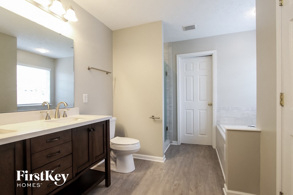 A bathroom with a toilet, sink, and mirror.