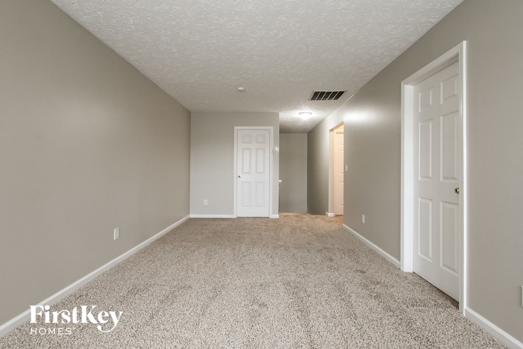 A room with a carpeted floor and two doors.