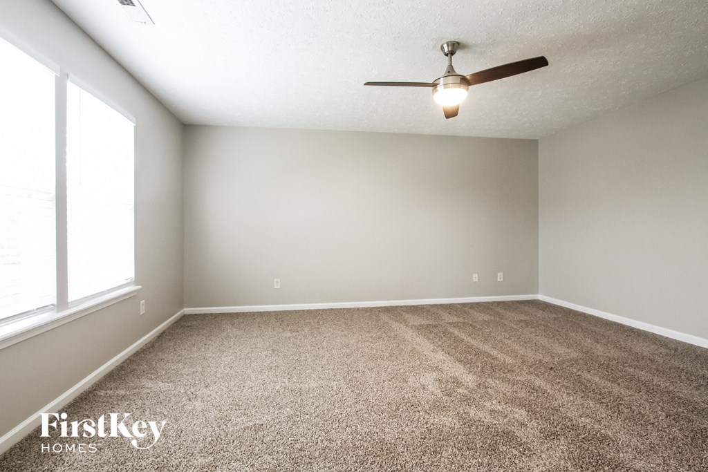 A room with a carpet floor and a ceiling fan.