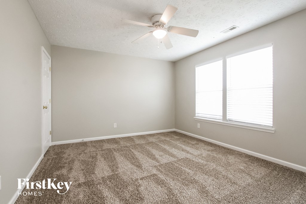 A room with a carpet floor and a ceiling fan.
