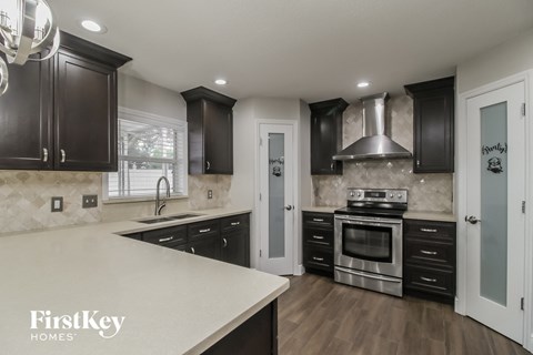 A modern kitchen with dark wood cabinets and stainless steel appliances.