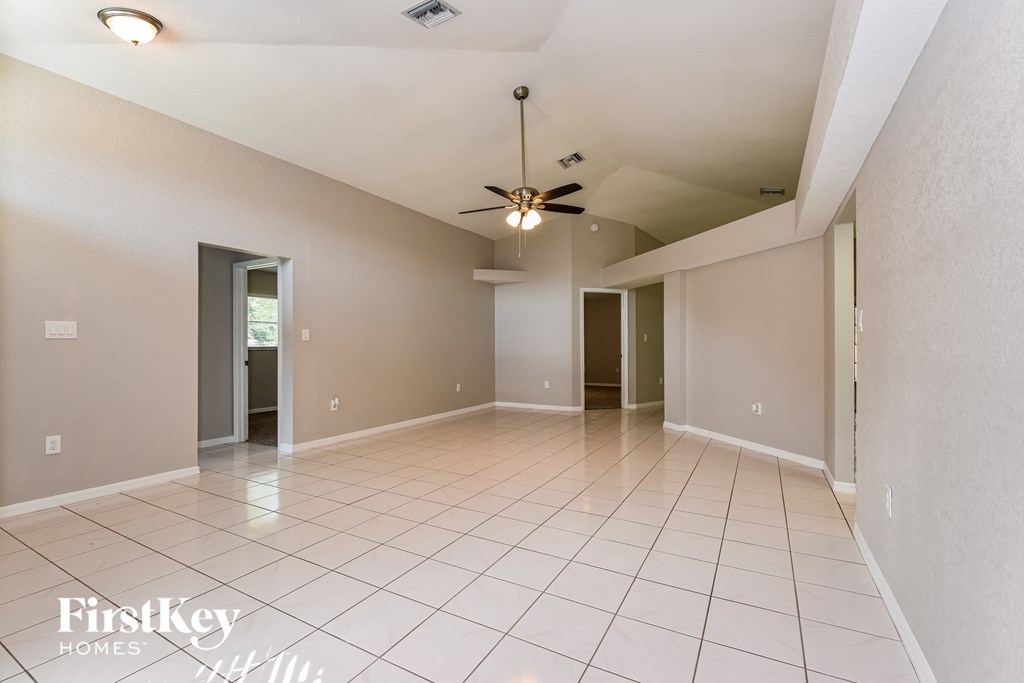 A spacious room with a ceiling fan and tiled flooring.