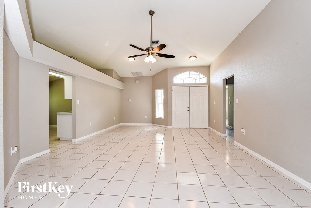 A spacious room with a ceiling fan and tiled flooring.