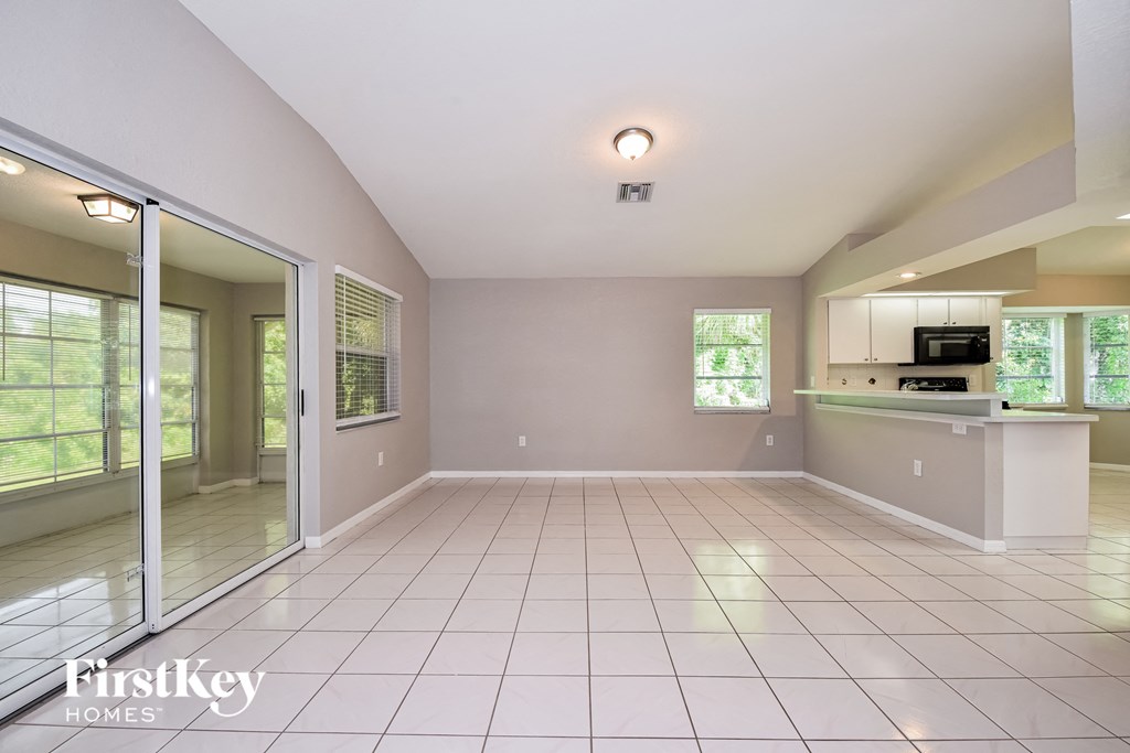 A spacious, empty room with a kitchenette and sliding glass doors leading to a patio.