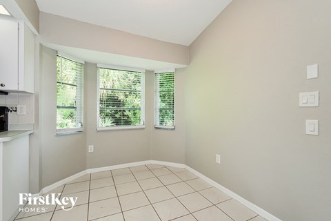 A room with a kitchen area and a window with blinds.
