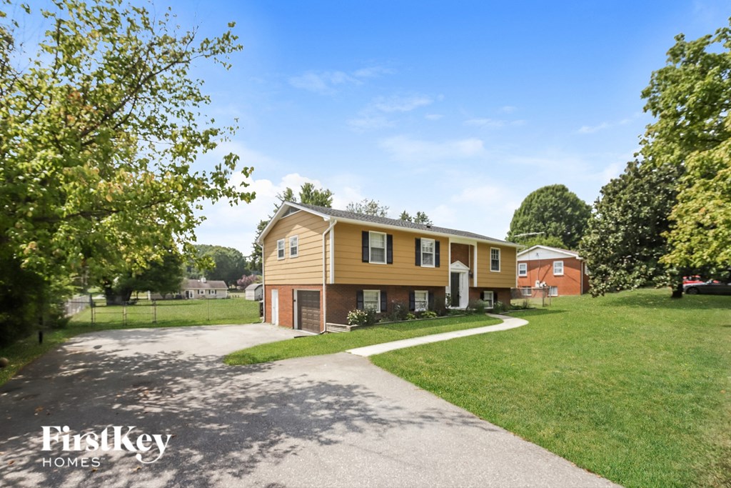 a yellow house with a sidewalk in front of a yard