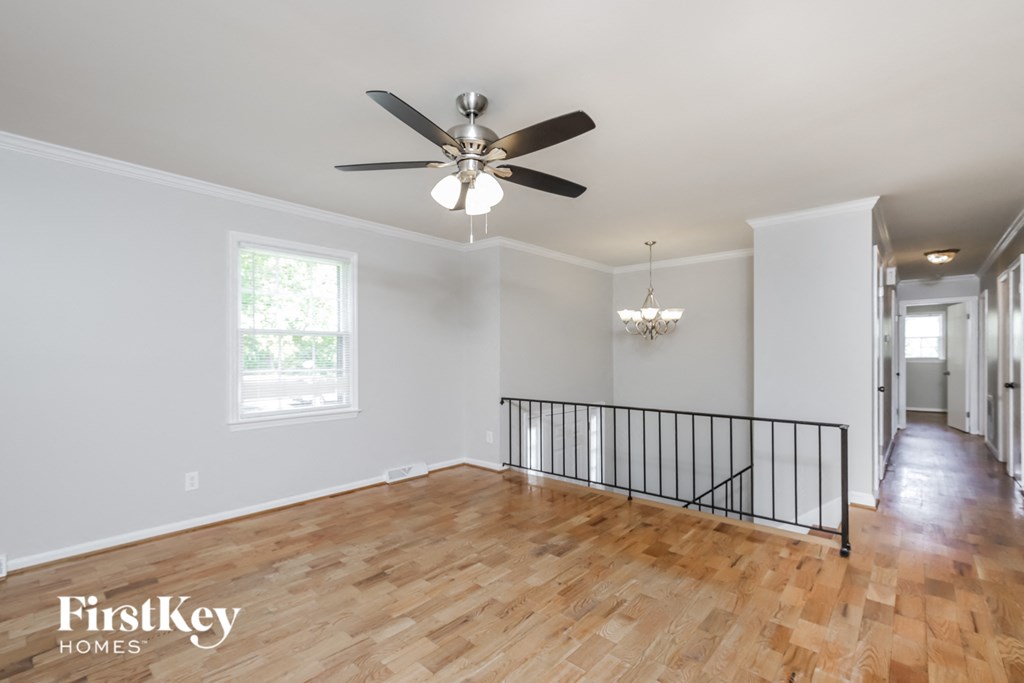 an empty living room with a ceiling fan and hardwood floors
