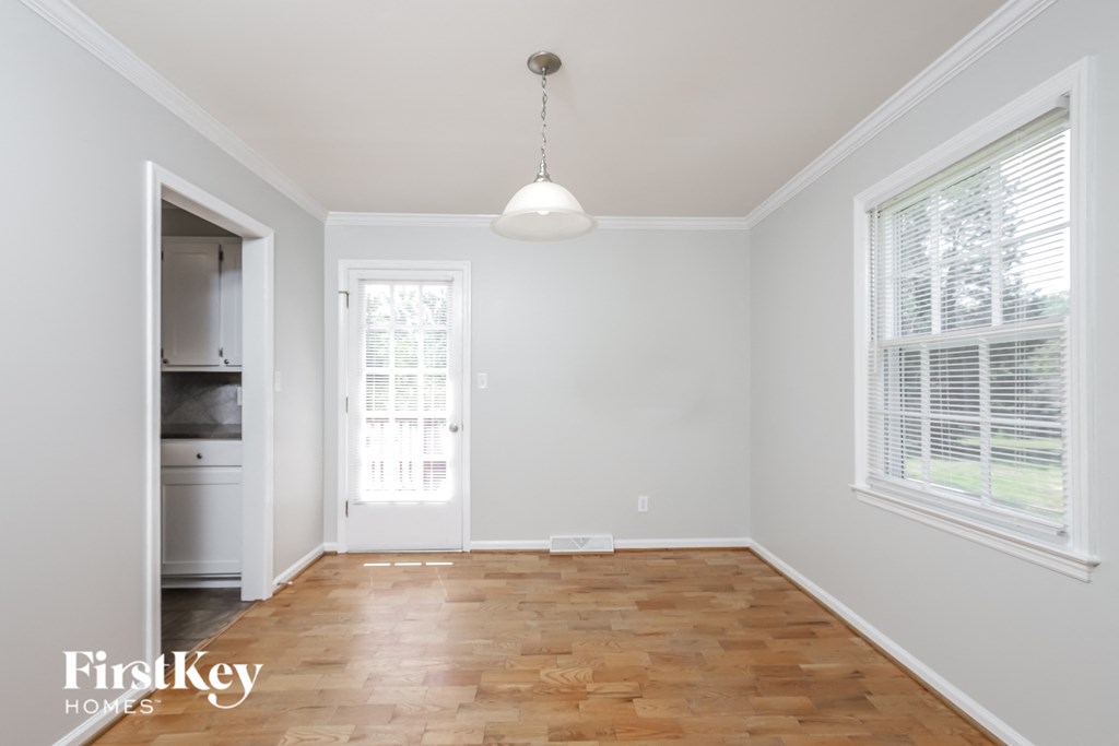 an empty living room with wood floors and a door to the kitchen