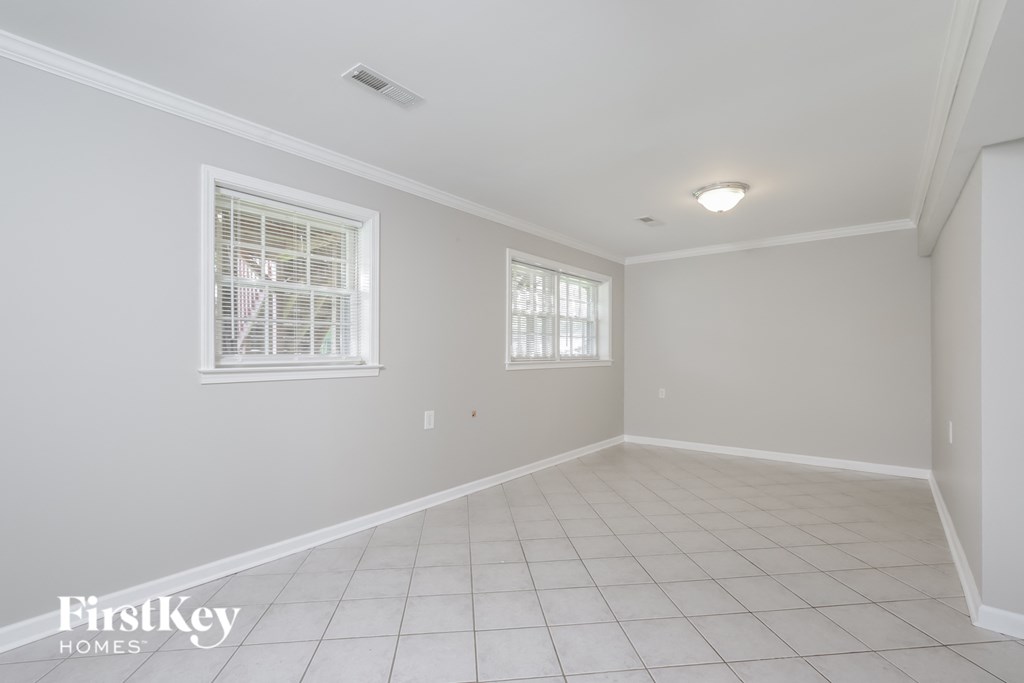 an empty living room with two windows and a tiled floor