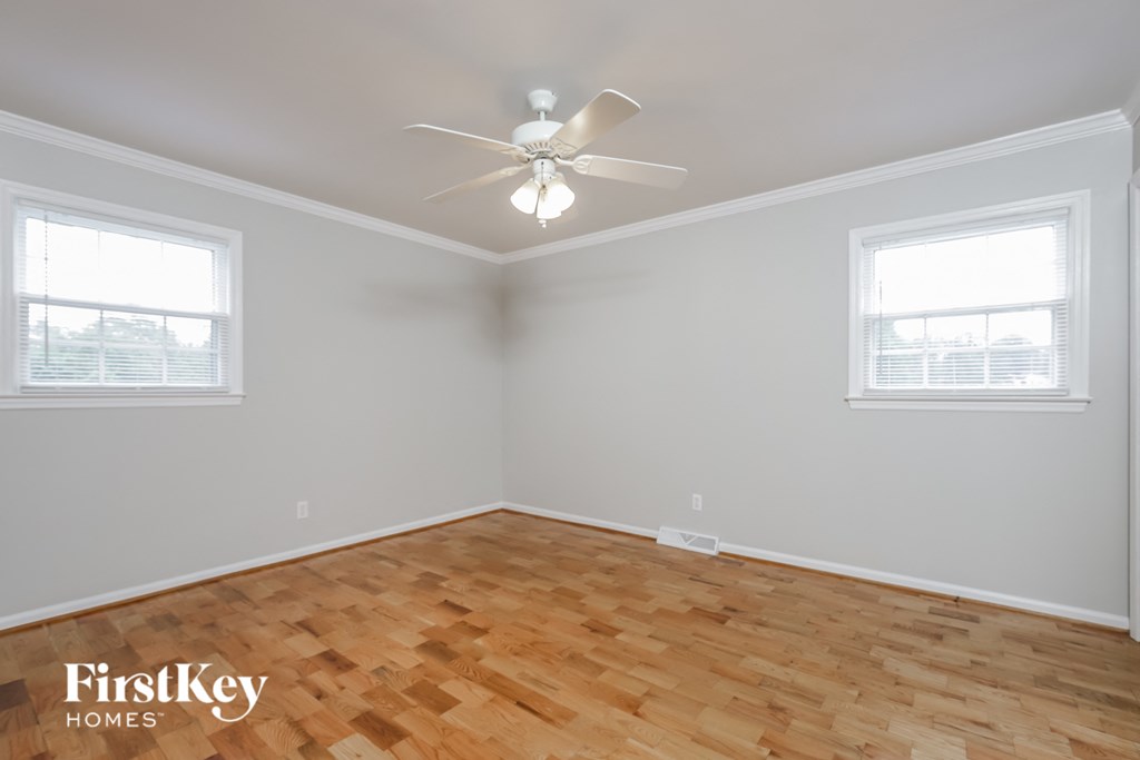 a bedroom with wood flooring and a ceiling fan