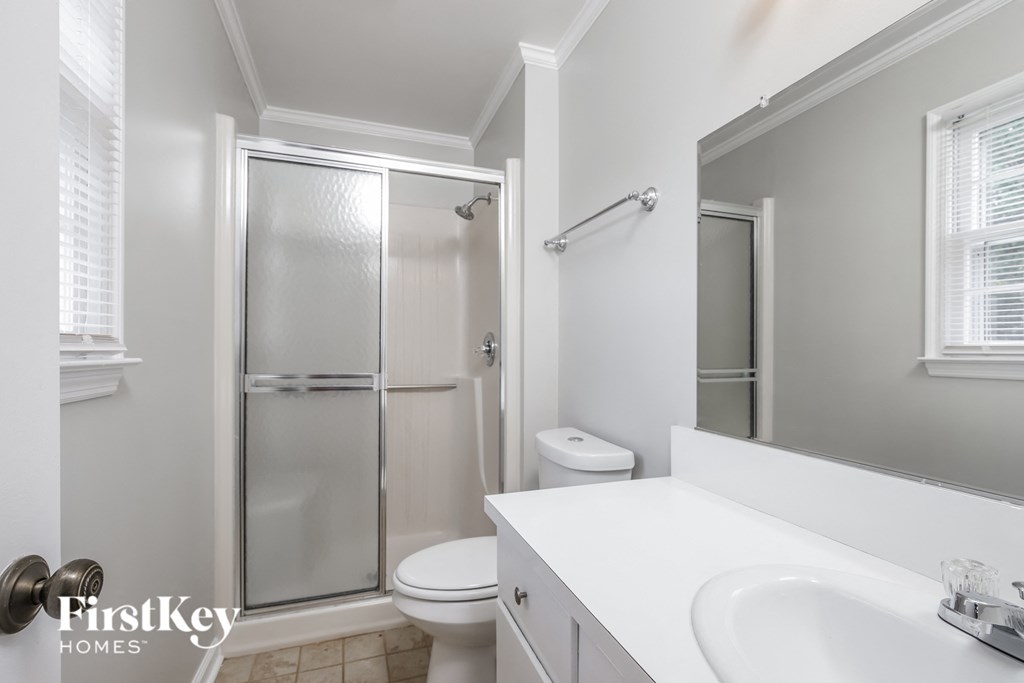 a white bathroom with a shower toilet and sink