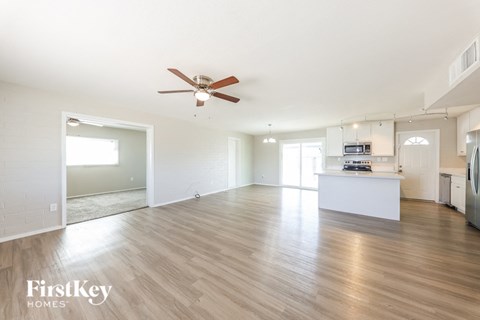 an empty living room and kitchen with a ceiling fan