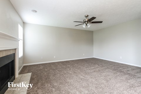 a living room with carpet and a ceiling fan