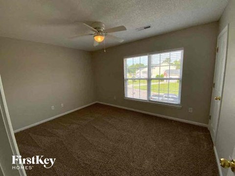 an empty bedroom with a ceiling fan and a window