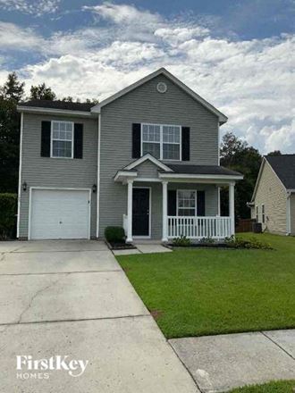 a gray house with a white front porch and a driveway