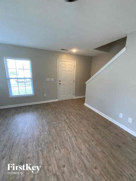 an empty living room with wood floors and a white door