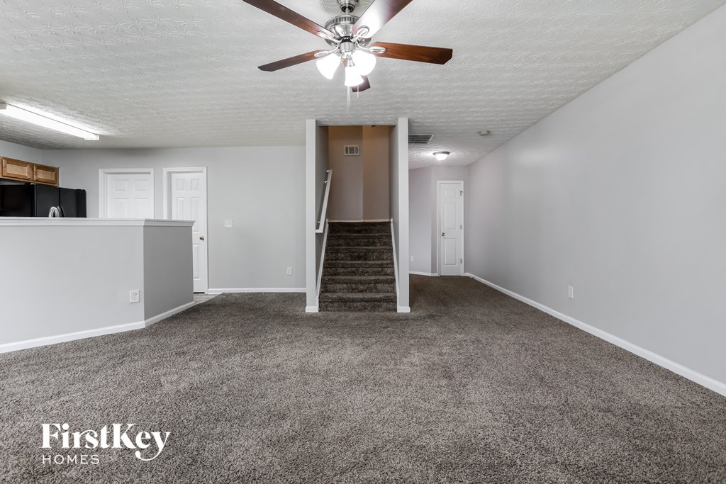 an empty living room with carpet and a ceiling fan