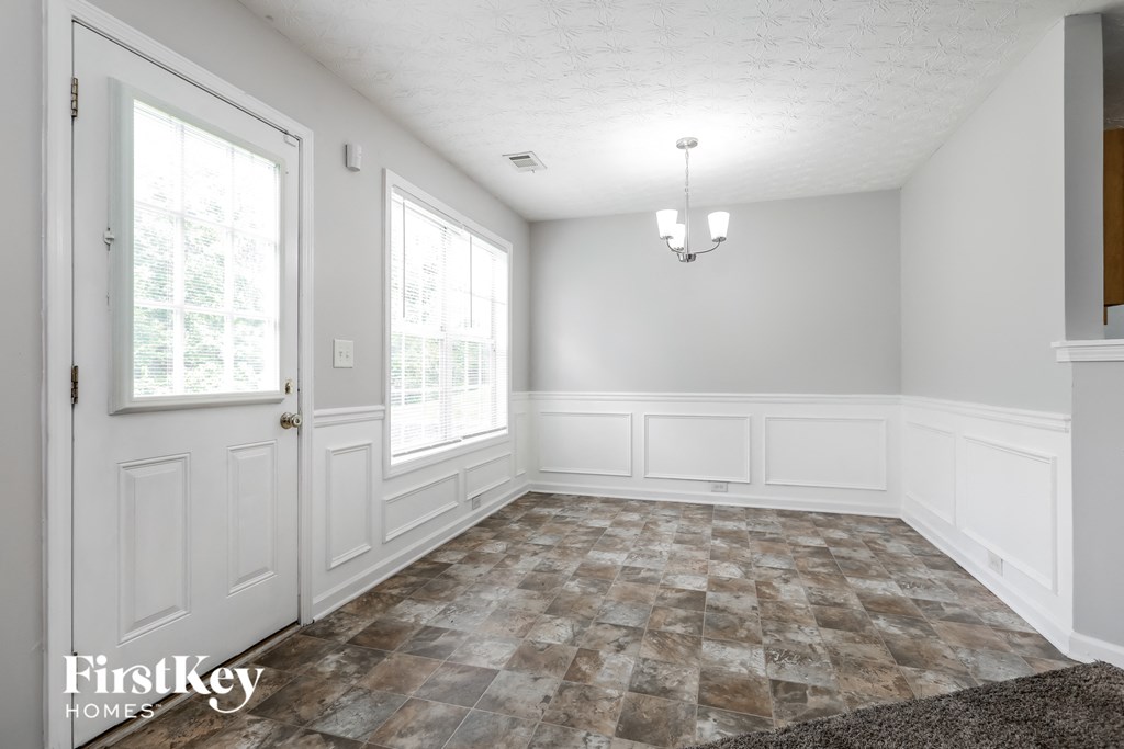 the living room of a home with white walls and a tiled floor