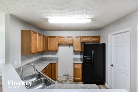 a kitchen with wooden cabinets and a black refrigerator