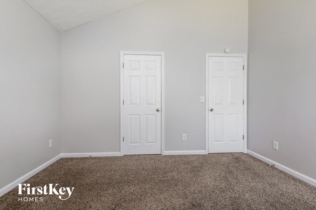 a bedroom with two white doors and a carpeted floor