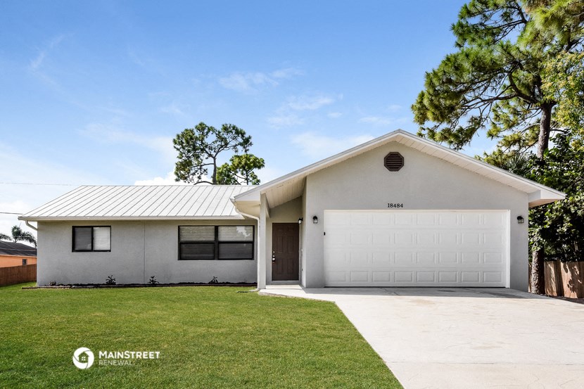 a white house with a white garage door and a lawn