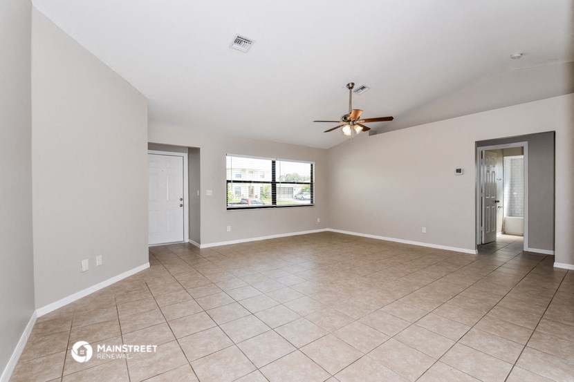 the living room of an empty house with a ceiling fan