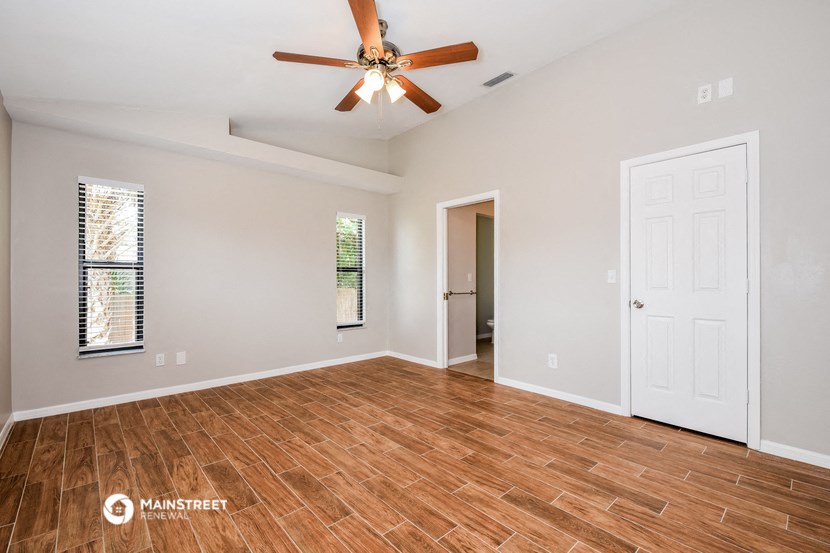 the living room with wood flooring and a ceiling fan