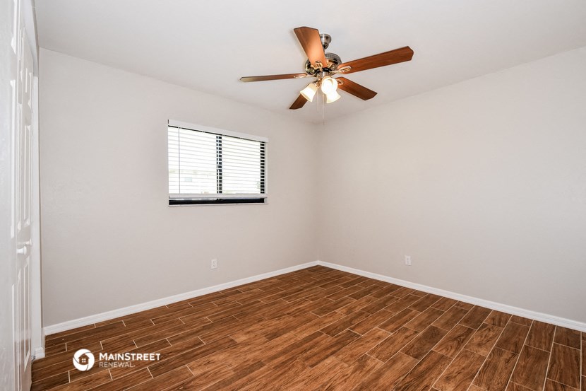 the spacious living room has hardwood floors and a ceiling fan