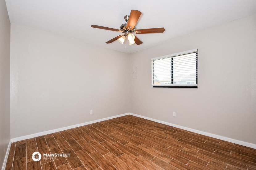 the living room with wood flooring and a ceiling fan