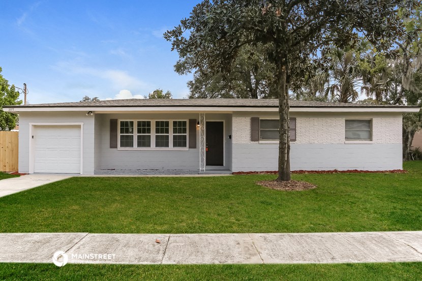 a white house with a lawn and a tree