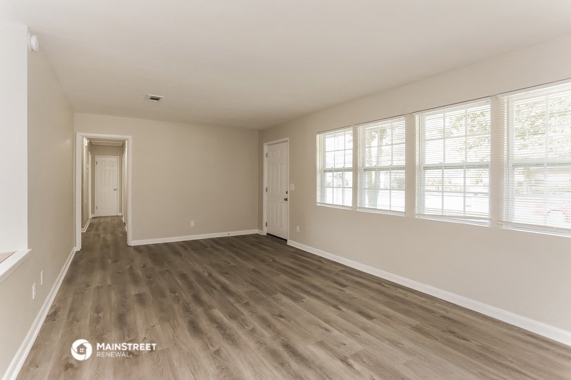 the spacious living room with wood flooring and large windows
