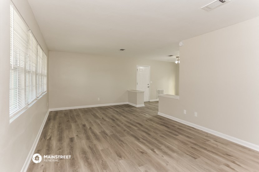 a spacious living room with wood floors and white walls