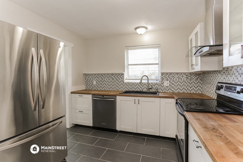 a kitchen with white cabinets and a stainless steel refrigerator