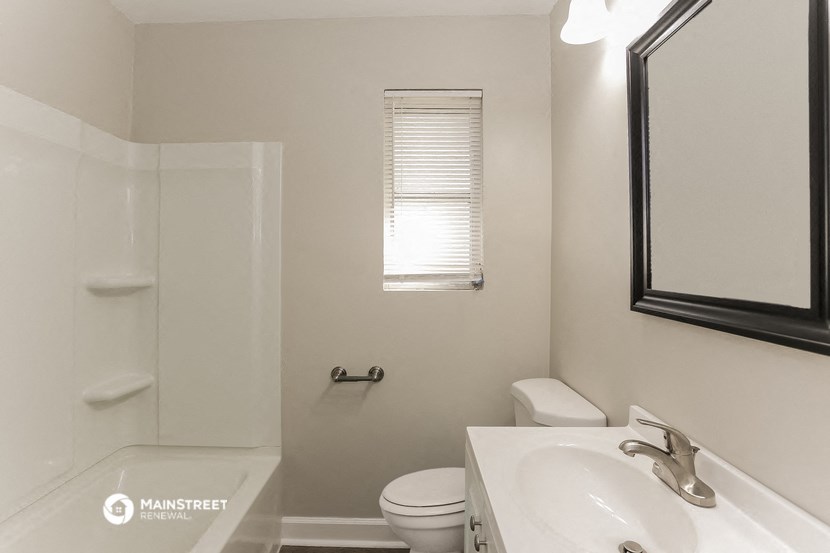 a bathroom with a toilet sink and shower and a mirror