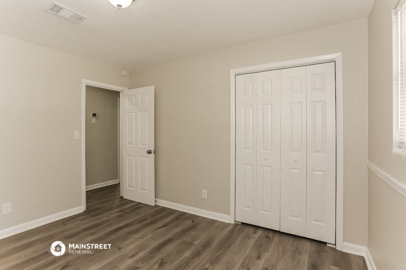 the living room of an apartment with white doors and wood floors