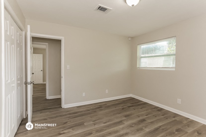 the spacious living room with hardwood flooring and a window
