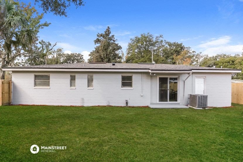 a small white house with a green lawn and trees