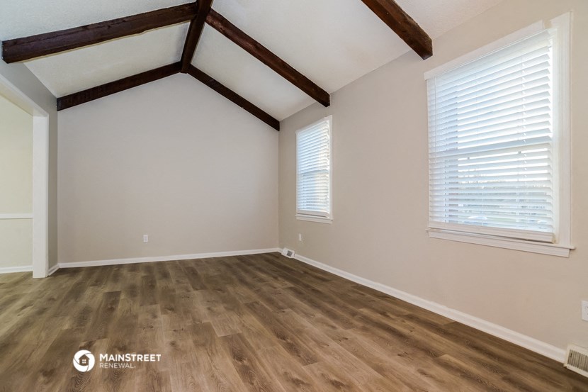 the upstairs bedroom with hardwood floors and a vaulted ceiling