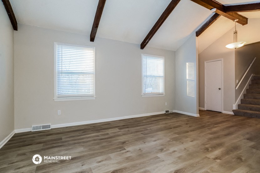 the ceilings in this spacious living room are exposed beams and the floors are wooden
