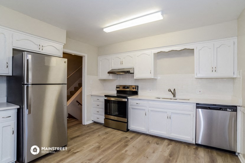 an empty kitchen with white cabinets and stainless steel appliances
