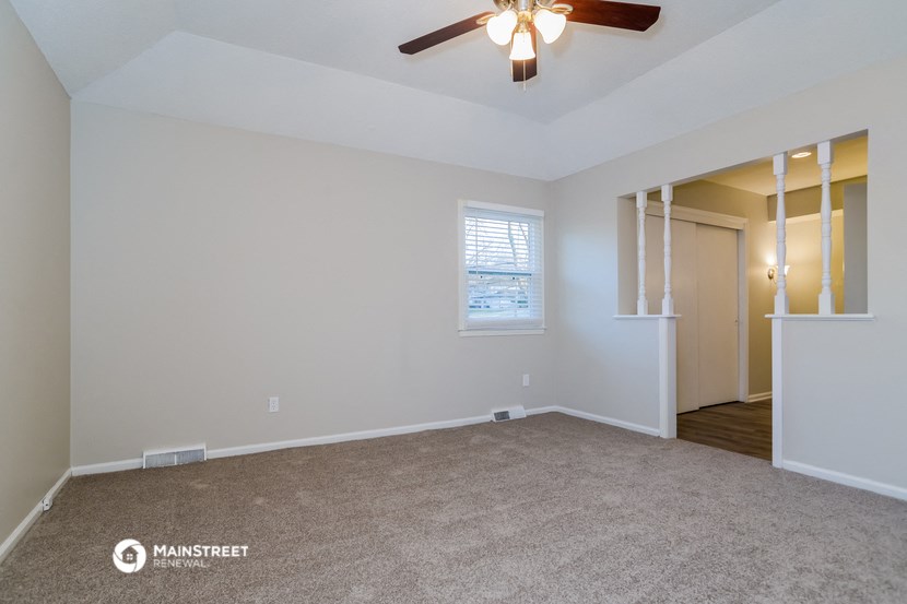 the living room of an empty house with a ceiling fan