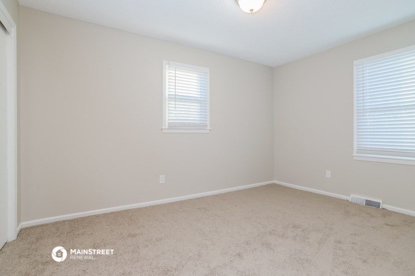 the upstairs bedroom with carpet and two windows