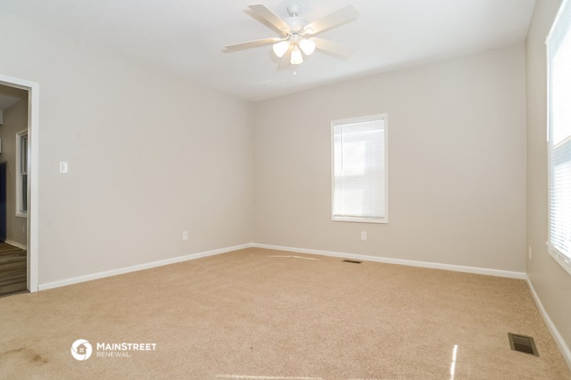 an empty room with a ceiling fan and a window