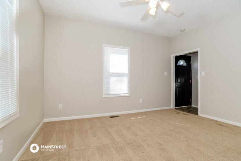 the spacious living room with carpeting and a ceiling fan
