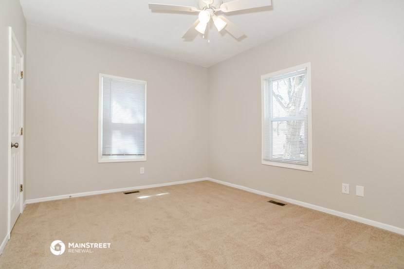 the spacious living room with carpeting and a ceiling fan