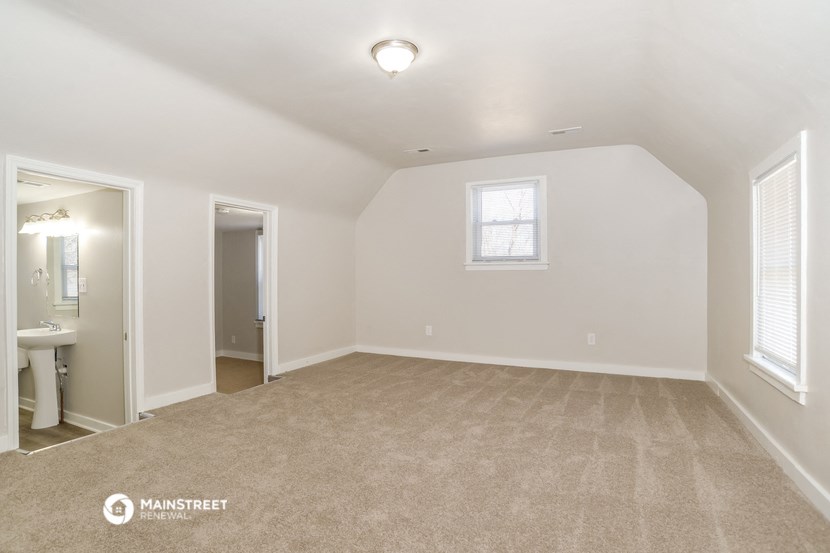 the spacious living room with carpeting and white walls